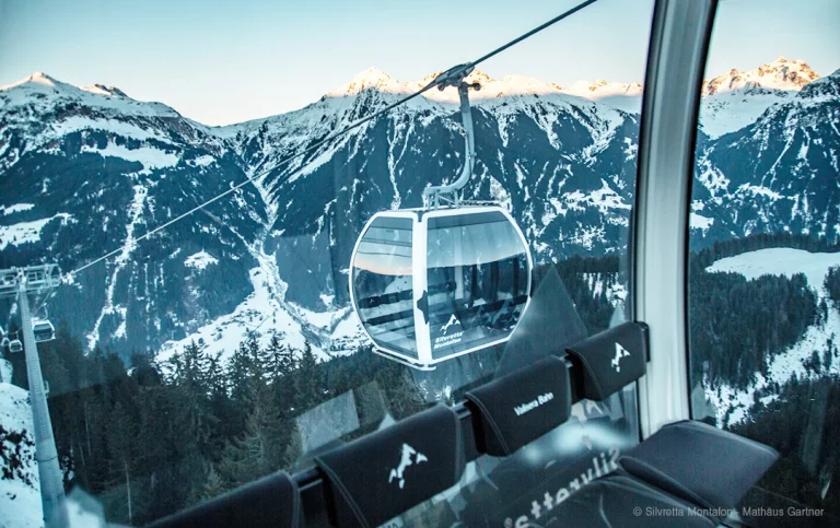 Omega V Kabine der Seilbahn Valisera Bahn mit Kabinengrafiken vor Bergpanorama mit Schnee und Sonnenschein in Österreich