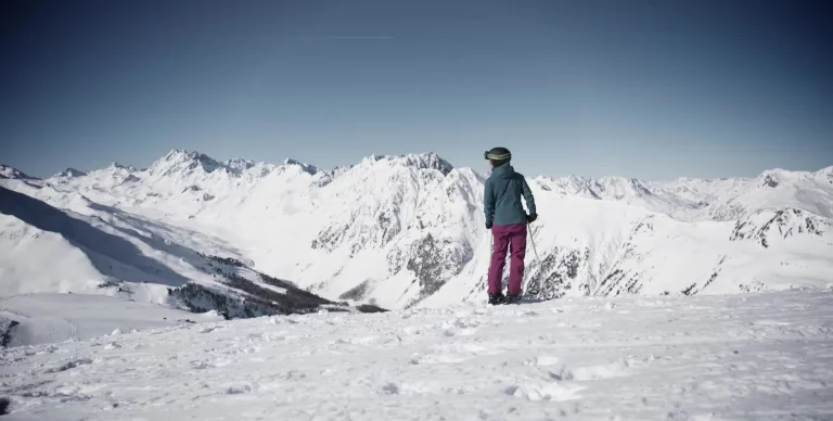 Bergpanorama mit Schnee und Skifahrerin in Ischgl